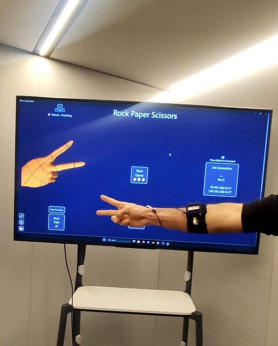 A person wearing the EMG bracelet controls the on-screen demonstrator with a hand gesture