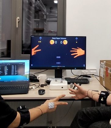 Two people each wearing EMG sensors play the game together